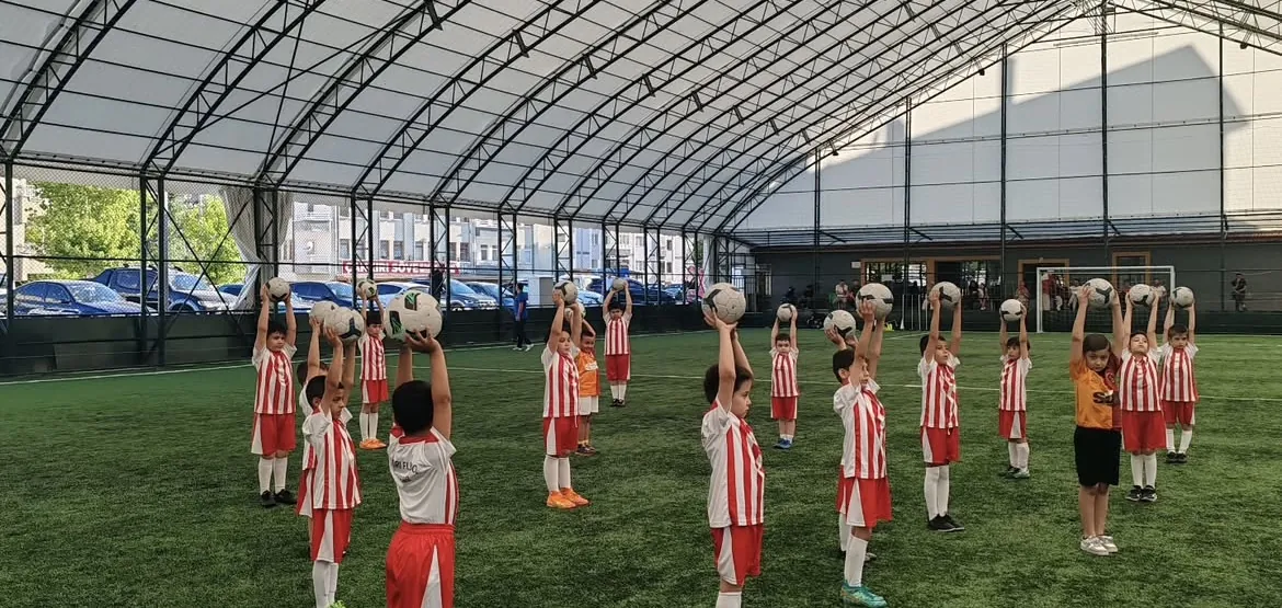 Akademi formasıyla topları başlarının üstüne kaldırmış öğrenciler